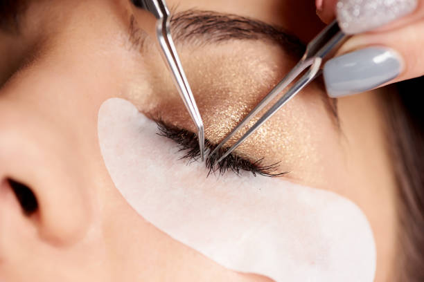 istock Brunette woman is getting eyelash extensions in a salon. Close-up 933271226
