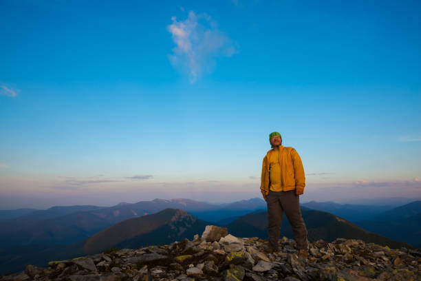istock Happy traveler stands on stony top during sunset 933283322