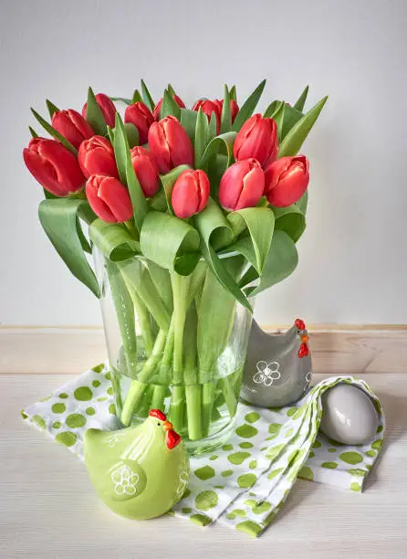 Easter background: bunch of red tulips, spring decorations on gray rustic background, text space