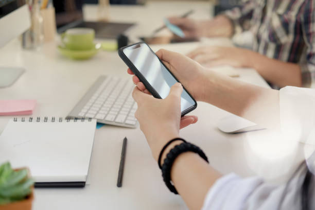 istock Woman texting on cell phone on desk in office. 933302586