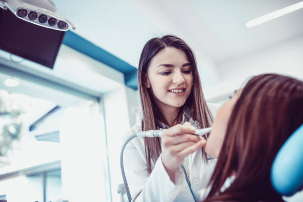 istock Smiling Dentist Examine Patients Teeth in the Clinic 933309772