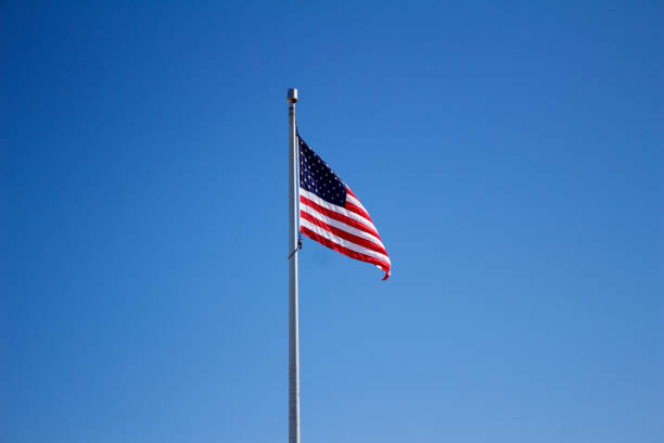 istock American flag on flagpole with blue sky background 933317616
