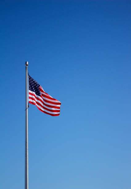 istock American flag on flagpole with blue sky background 933320672