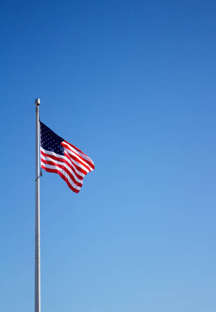 istock American flag on flagpole with blue sky background 933320772