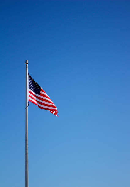 istock American flag on flagpole with blue sky background 933321186