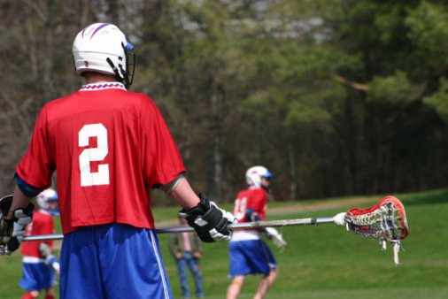 Lacrosse player running and scooping up the ball during a game