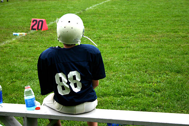 istock Football player sitting on a bench next to the field 93332507