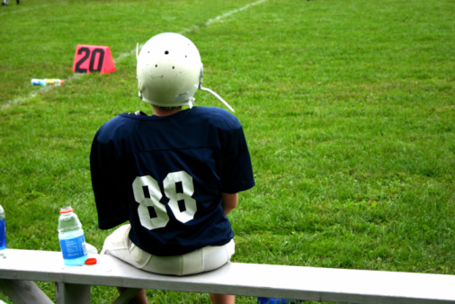 young football player sitting on the bench