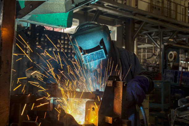istock Worker is welding metal part in factory 933325906