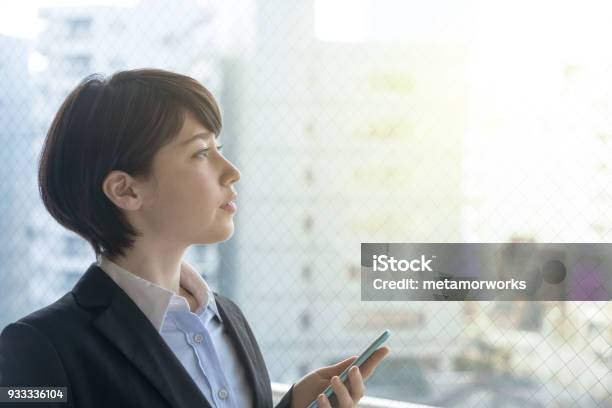 Young Woman Holding Smart Phone In The Office Stock Photo - Download Image Now - Japanese Ethnicity, Women, Business