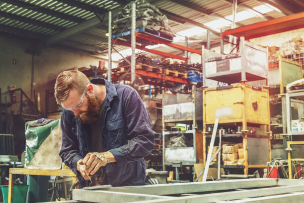 istock Young Metal Worker Using Power Tool In Factory With Protective Equipment 933344826