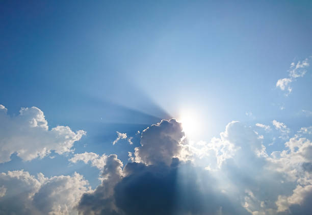 istock White fluffy clouds and sun reflect, in the blue sky 933347772