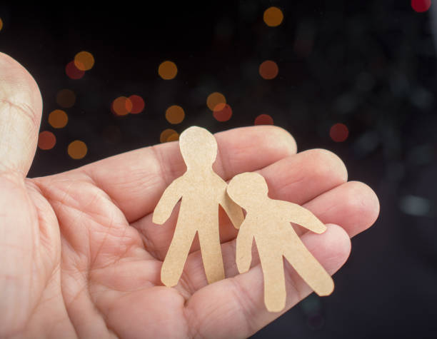 istock Paper man shape in hand on bokeh light background 933353392