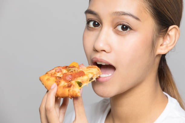 istock Young woman eating a slice of pizza. 933380138
