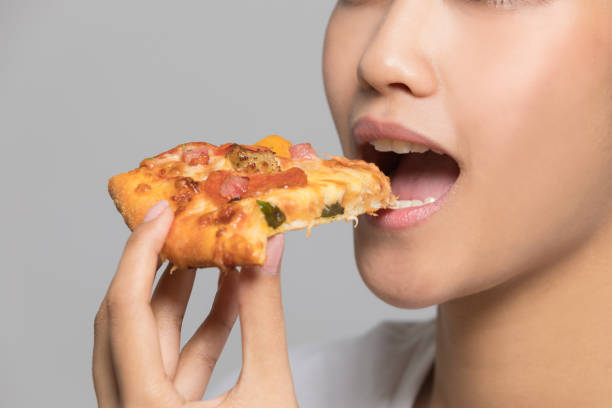 istock Young woman eating a slice of pizza. 933380186