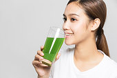 野菜ジュースのガラスを飲む若い女性。