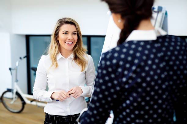 istock Two young women standing in front of whiteboard in modern office 933386302