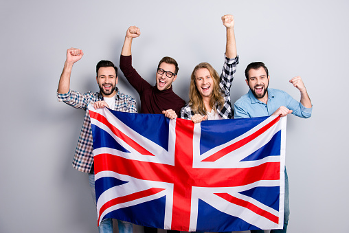 International ethnicity language learn course university concept. Friendly excited cheerful guys screaming rejoicing putting fists up triumphing holding jack union flag isolated on gray background