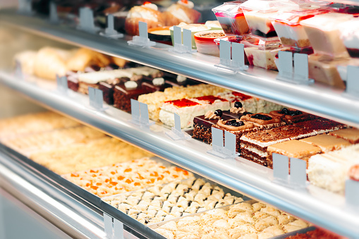 Cake display,Pastry shop glass showcase different types of cakes,Pastry shop display with assorted cakes,Exterior view of the cake on a bakery shelf