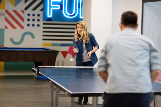 jeune femme jouant au tennis de table avec son collègue - tennis de table photos et images de collection