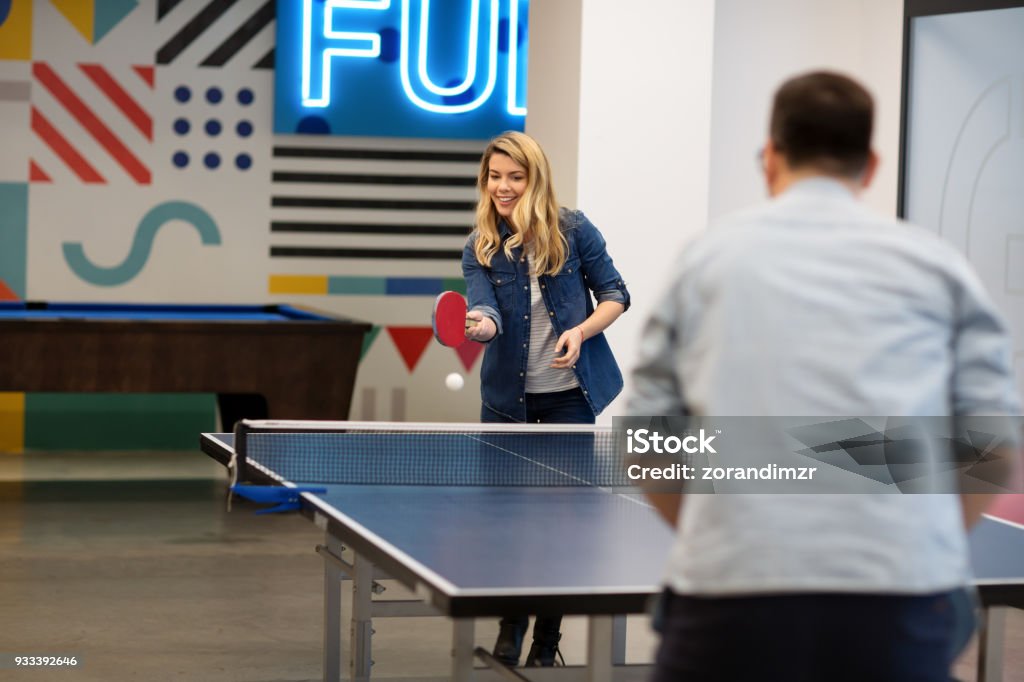 Young woman playing table tennis with her colleague Table Tennis Stock Photo