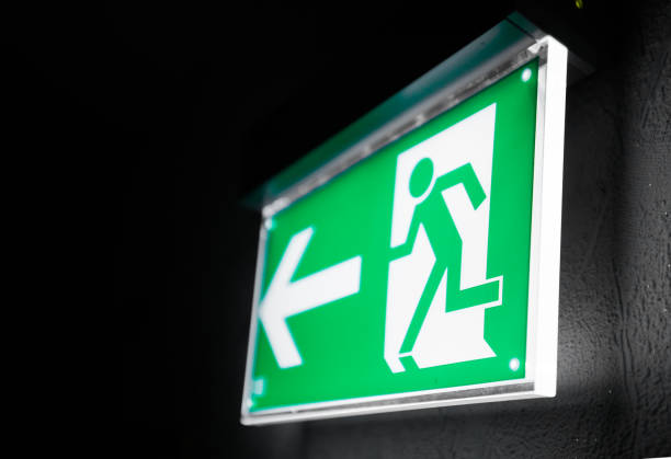 Illuminated Green Emergency Exit Sign Modern green emergency exit sign above a black doorway exit sign photos stock pictures, royalty-free photos & images