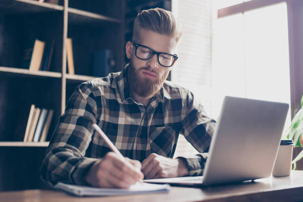 istock High-school campus nerd intelligence leadership people copybook notepad concept. Portrait of concentrated focused intellectual stylish brutal calm student doing hometask in cafe drinking tea 933399490