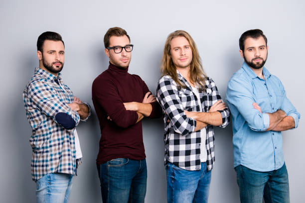 istock Community university glasses work colleagues authority concept. Half-turned four virile guys standing with folded arms, checkered denim jeans shirt spectacles isolated on gray background 933402342