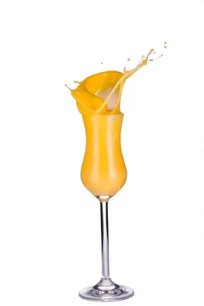 Glass of egg liqueur splashing isolated on white background, close-up, front view