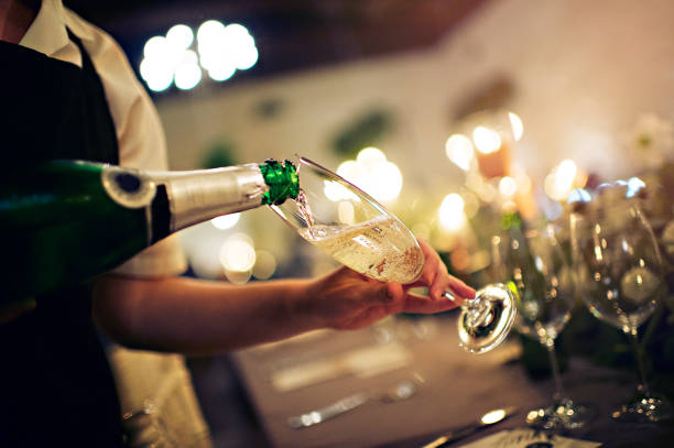 Waiter pour into a glass of champagne stock photo