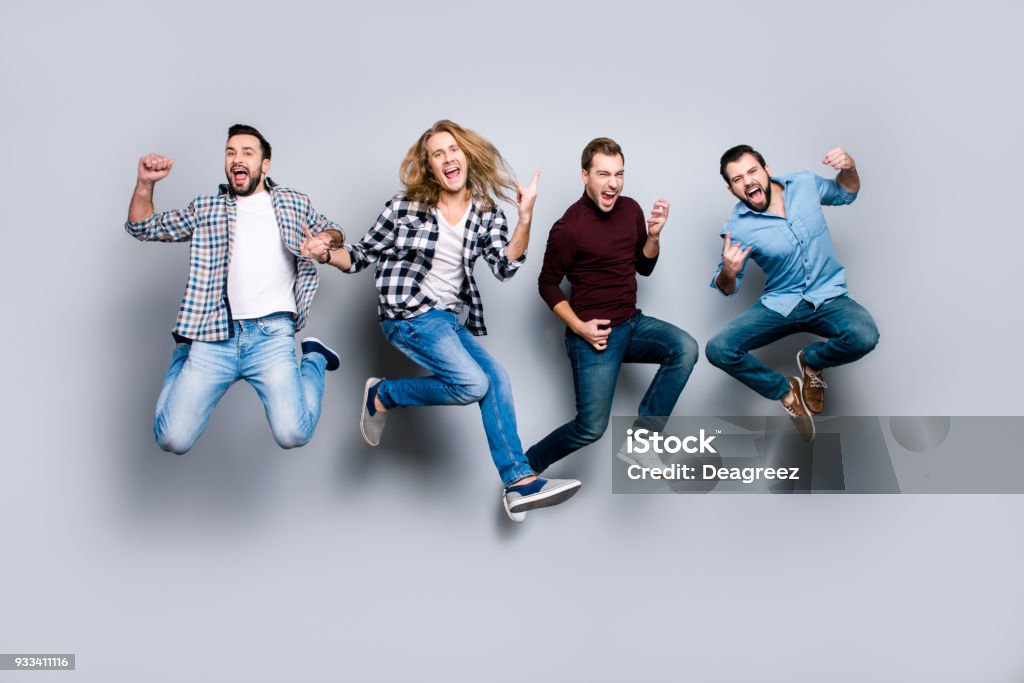 Ethnicity diversity careless freedom people chill hang-out figure playful funny showing symbols concept. Four excited cheerful active carefree men jumping up isolated on gray background Teamwork Stock Photo