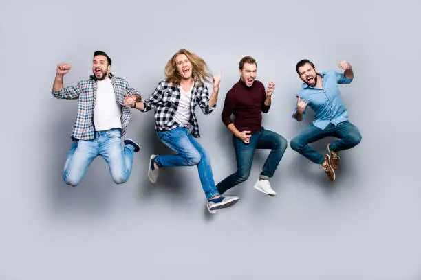 Ethnicity diversity careless freedom people chill hang-out figure playful funny showing symbols concept. Four excited cheerful active carefree men jumping up isolated on gray background