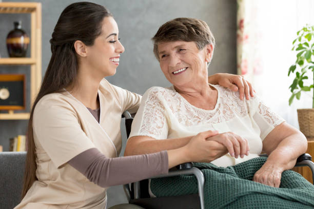 istock Nurse supporting happy elderly woman 933417408