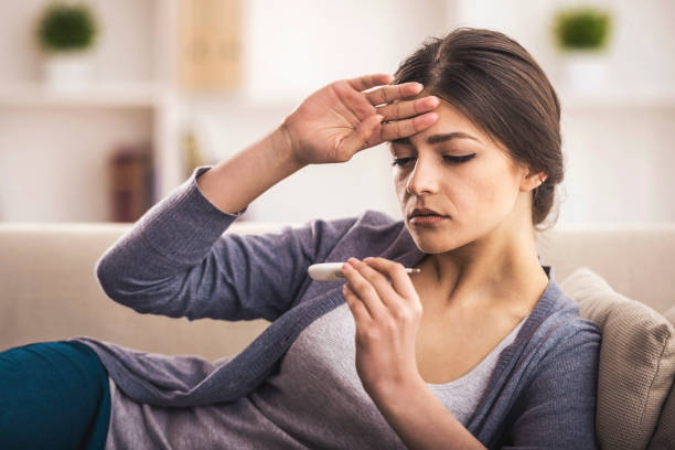 Disease Young woman is looking at the thermometer. She has fever. fever stock pictures, royalty-free photos & images