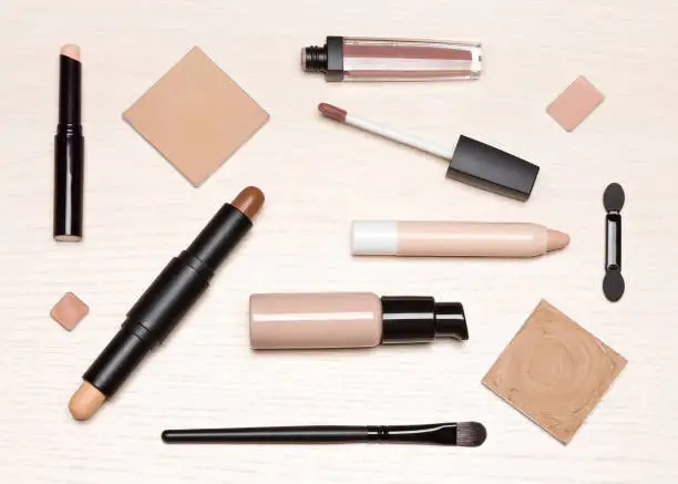 Photo of Basic makeup cosmetic products on light wood table flat lay