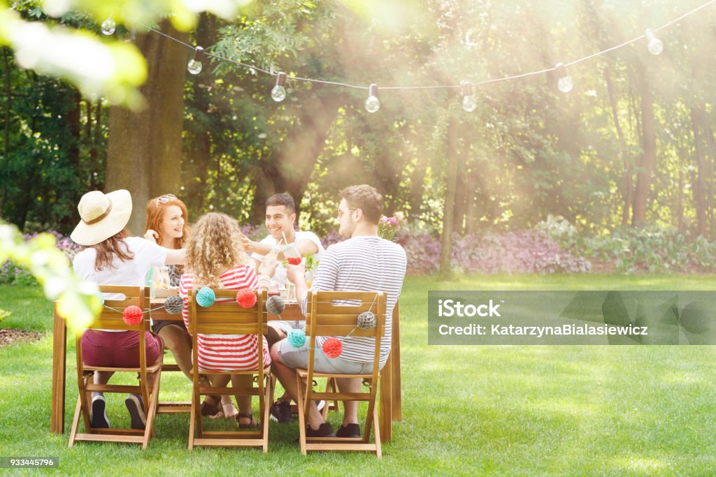 Smiling friends during garden party Group of smiling friends eating lunch during garden party Summer Stock Photo