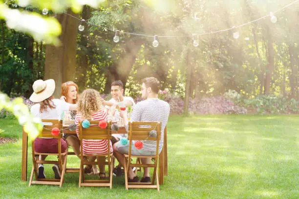 Group of smiling friends eating lunch during garden party