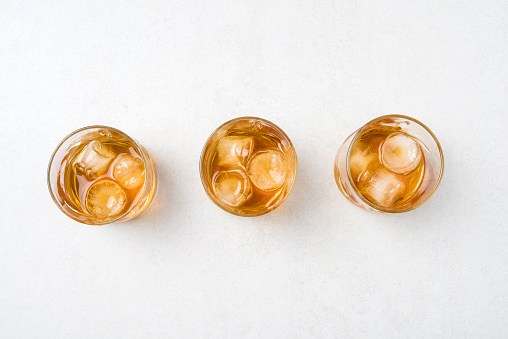 Whiskey glasses with ice cubes on white background