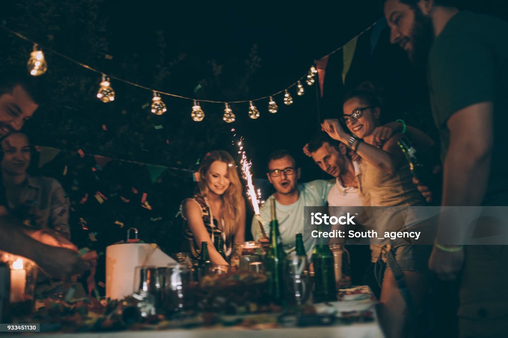 Happy friends at b-day party Group of young people enjoying the birthday party in backyard at night Dinner Stock Photo