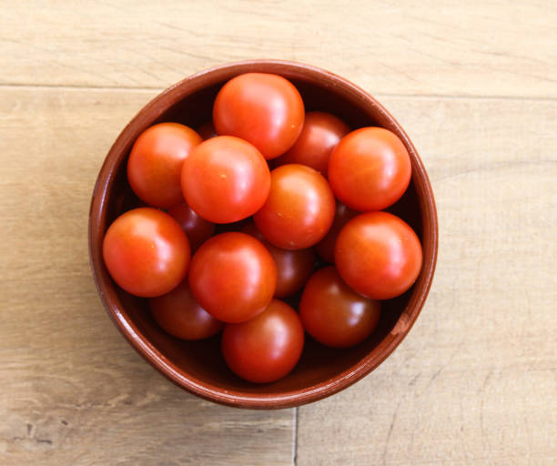istock Stone bowl with Cherry tomatoes on wooden background in kitchen 933453754
