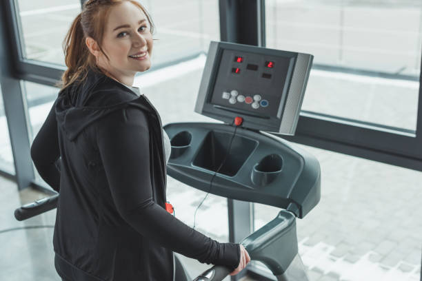 istock Curvy girl smiling while on treadmill in gym 933454656