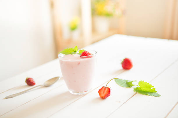 Fresh homemade yogurt with strawberries on a white wooden table.