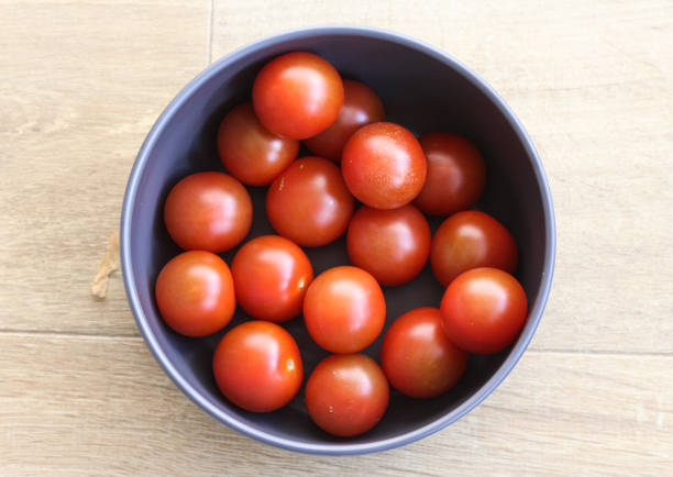 istock Cherry tomatoes on wooden background in kitchen 933458022