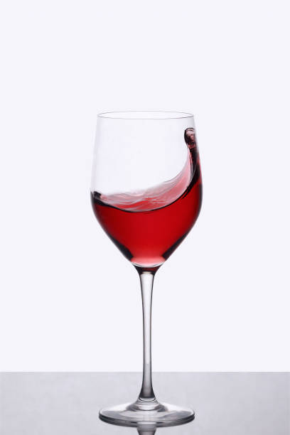 istock red wine swirling in a wine glass standing against light background 933459274