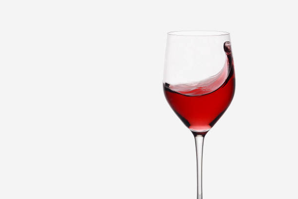 istock red wine swirling in a wine glass standing against light background 933461372