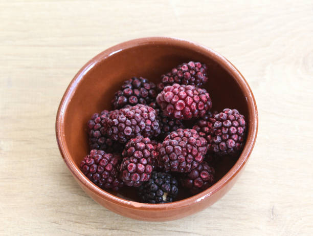 istock Bowl with Frozen blackberries on wooden background in kitchen 933463076