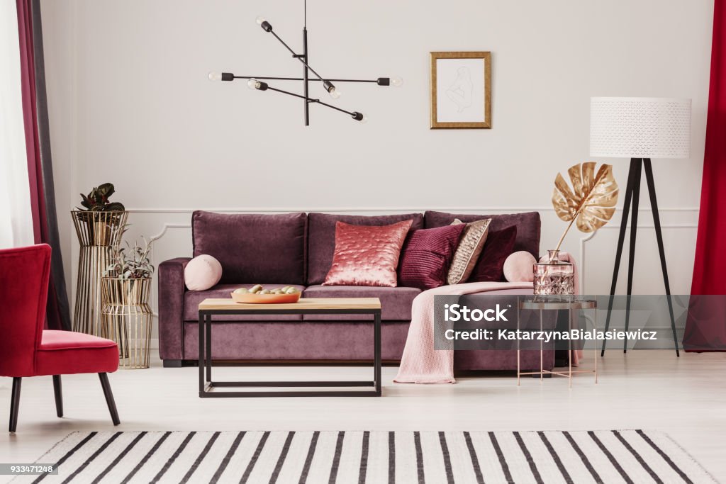 Sophisticated living room interior Gold leaf on copper table in sophisticated living room interior with striped carpet and violet sofa Purple Stock Photo