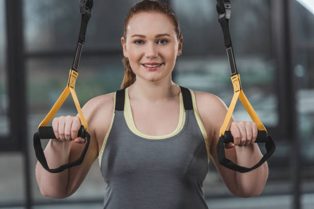istock Obese girl training on elastics in gym 933478348