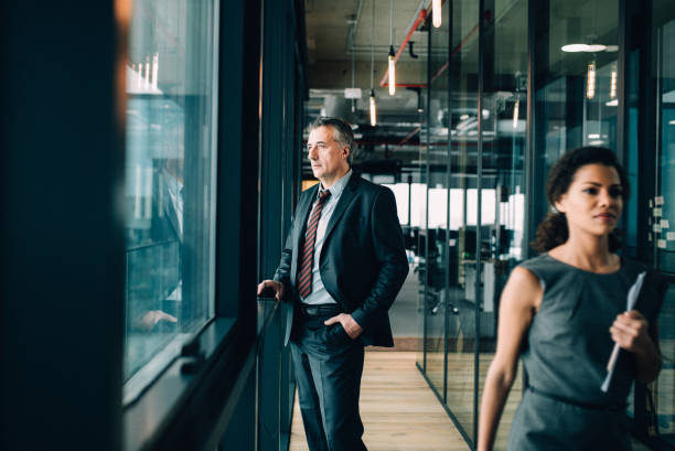 Thoughtful senior businessman Senior businessman in suit looking out of window african american architecture stock pictures, royalty-free photos & images