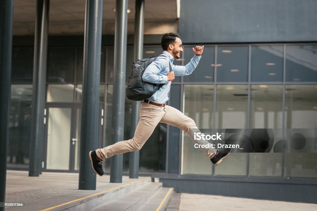 Businessman is running to catch the train Successful 30 year old businessman dressed in smart casual clothing going for short business trip by train and local transportation. Jumping Stock Photo